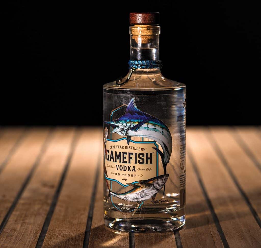 Cape Fear Distillery’s GameFish Vodka on a wooden table with a black background.
