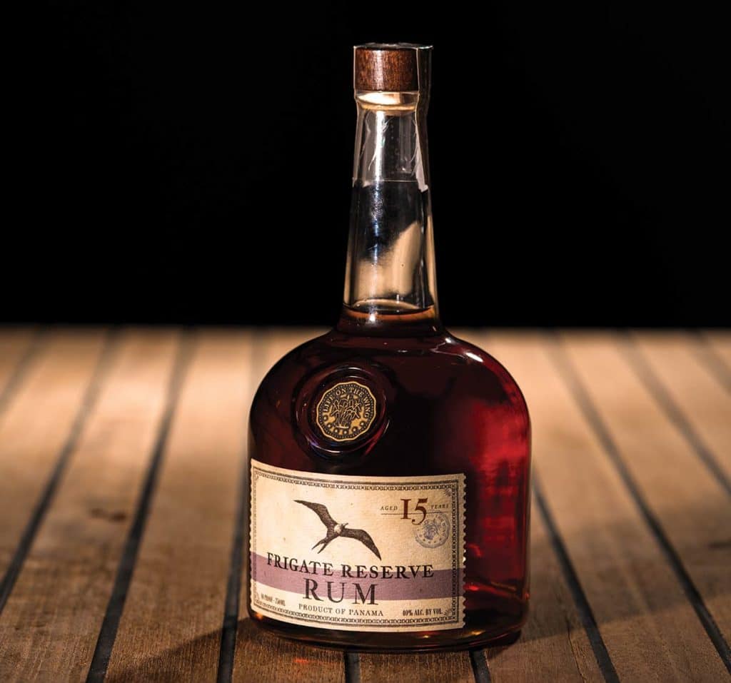 Frigate Reserve Rum on a wooden table with a black background.