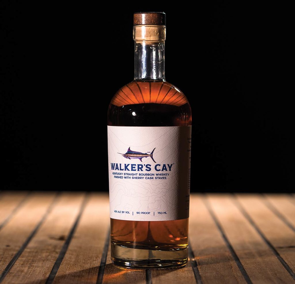 Walker’s Cay Bourbon on a wooden table and black background.