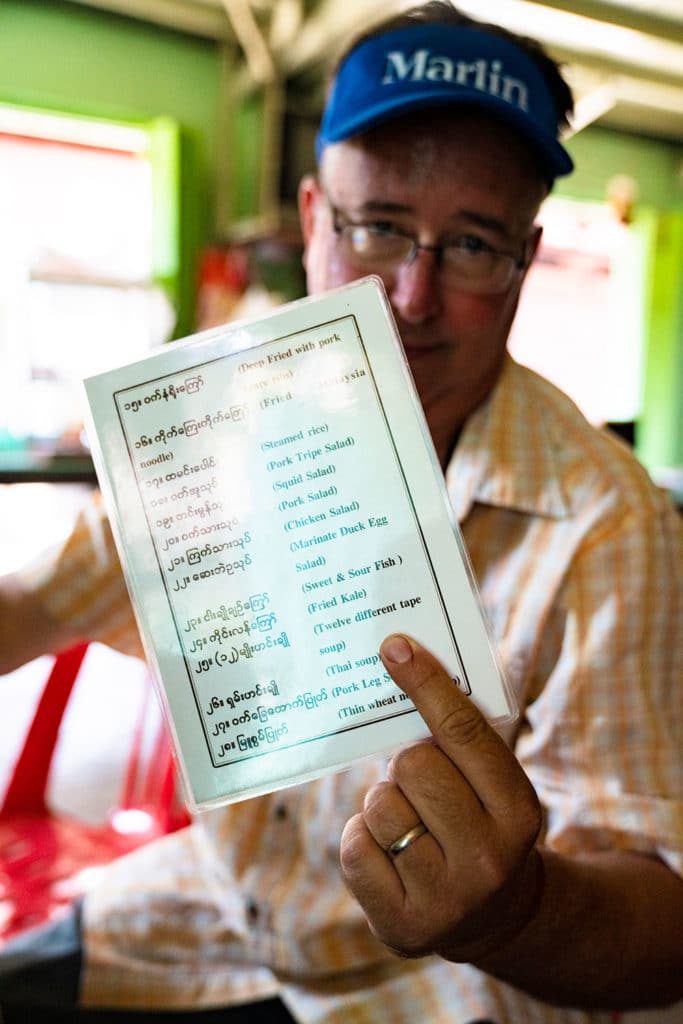 man holding up a menu in the myanmar markets