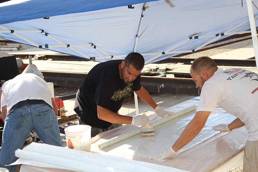 team applying fiberglass to boat hull