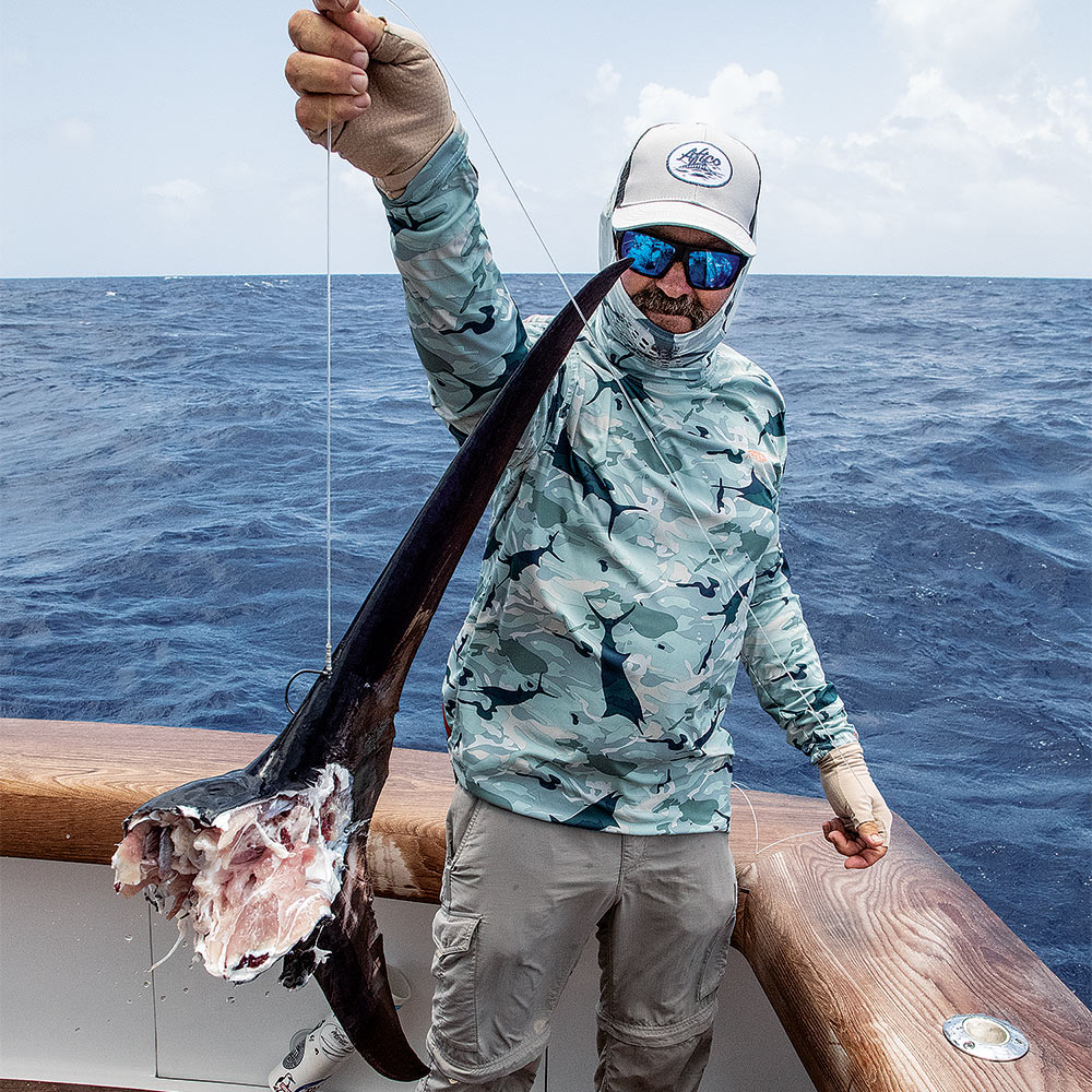 man holding up a shark bitten marlin tail
