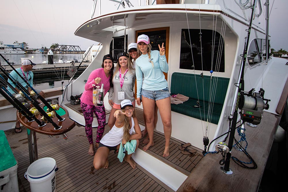 group of girls holding a bag of champagne on a boat deck