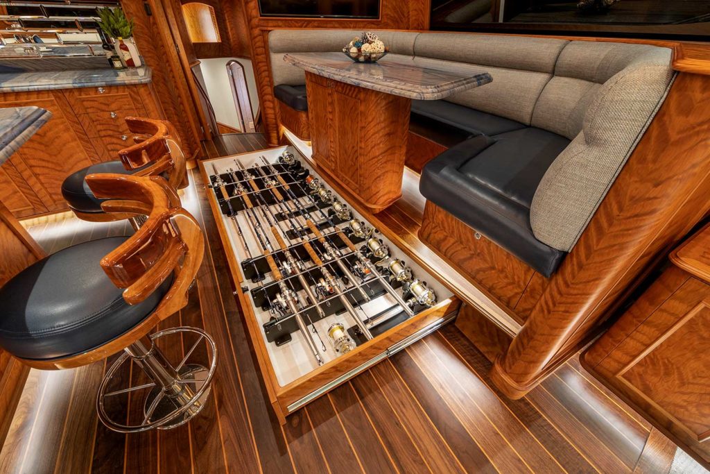 A pull-out draw in the interior lounge of a sport fishing boat that is filled with extra fishing rods and reels.