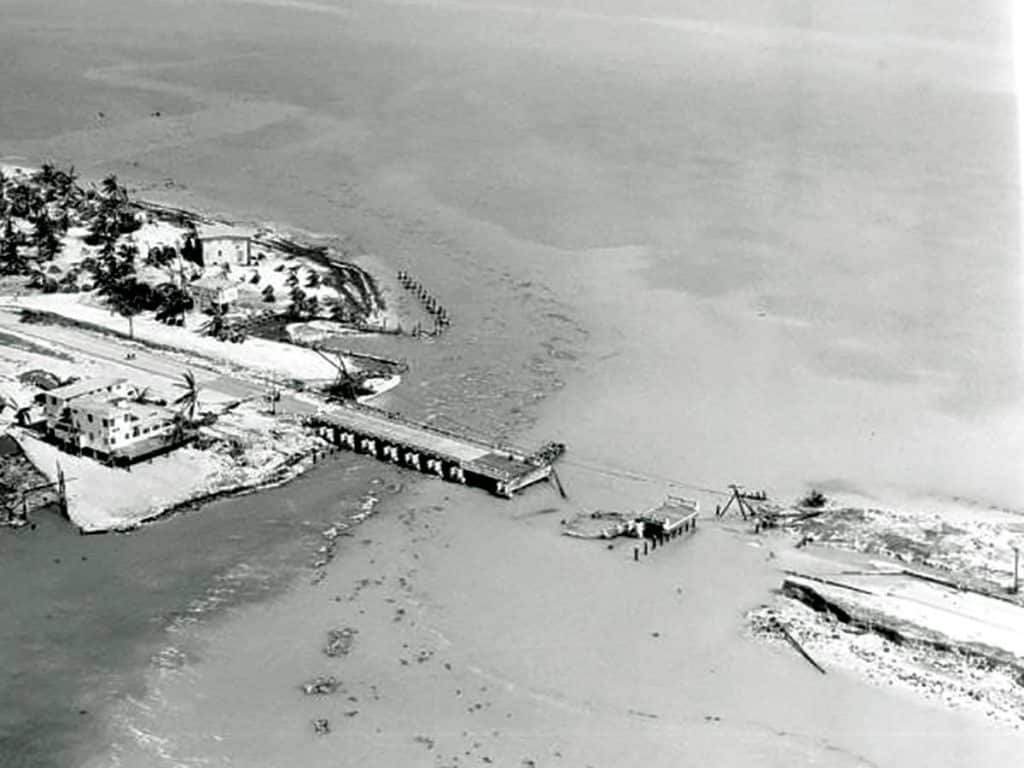 An aerial black and white photo of a collapsed bridge.