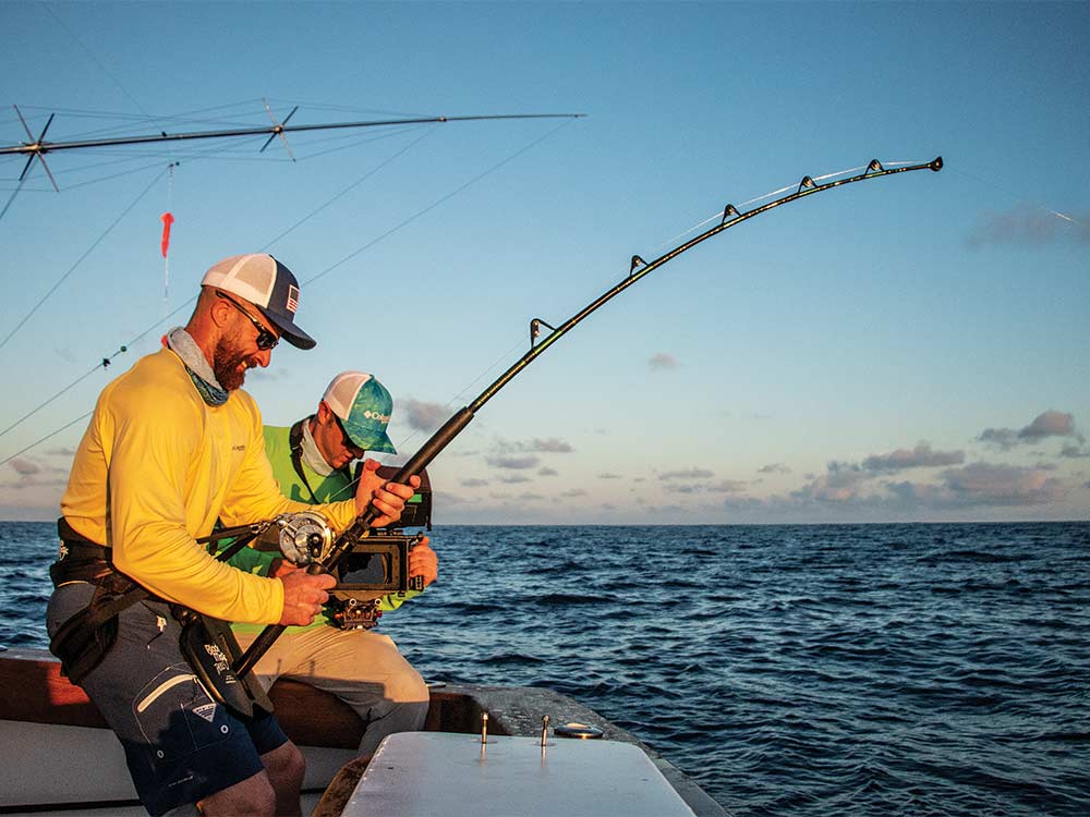 fisherman handling a fishing reel with a blue marlin on the line
