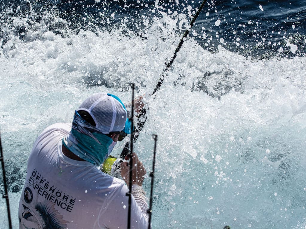A sport-fisher fights to reel in a fish in the ocean.