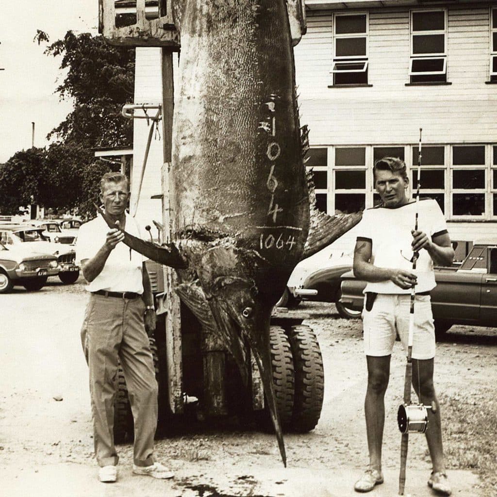 Two men stand beside a large world-record black marlin.