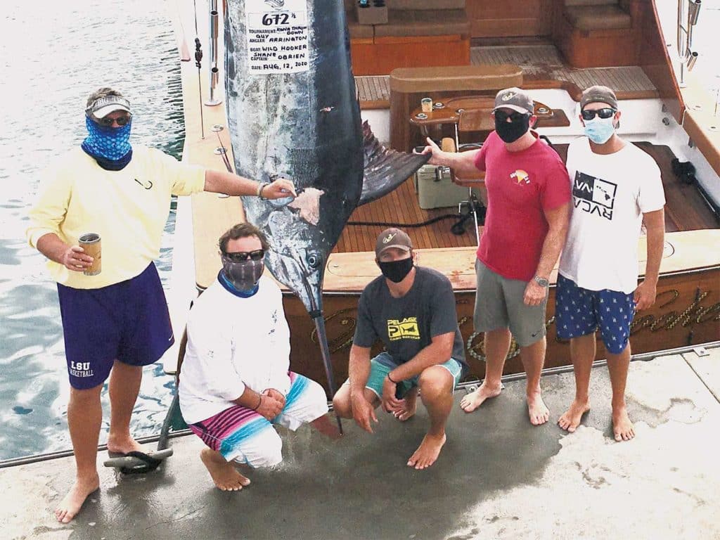 A group of anglers standing next to a large marlin.