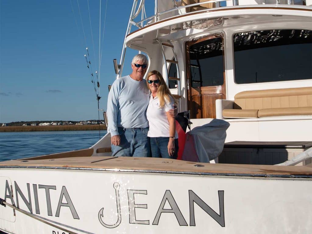 A man and a woman stand on the boat deck of their Winter Custom Yacht.