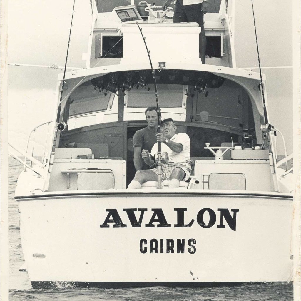 A black and white image of two people fishing on the Avalon sport-fishing boat.