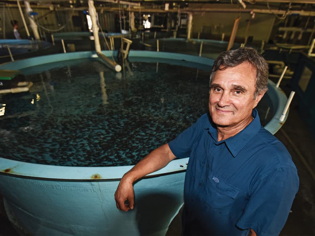 Bill Shedd leans next to a large aquaculture vat of water.