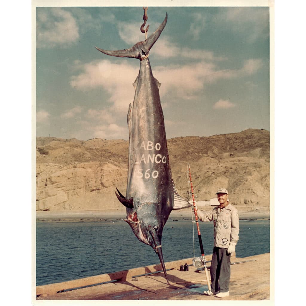 Sepia-toned photograph of a large black marlin and an angler.