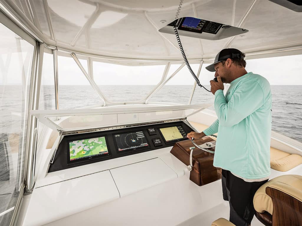 A boat captain using marine electronics at the helm of a boat.