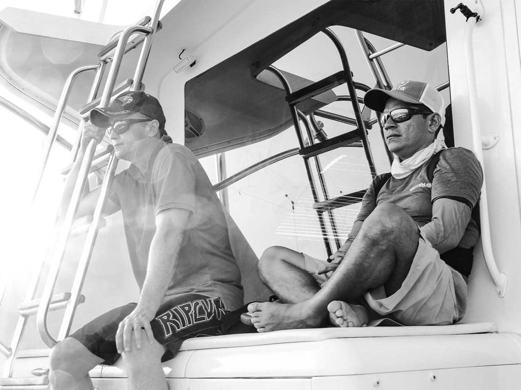 black and white image of two men sitting on a boat's mezzanine