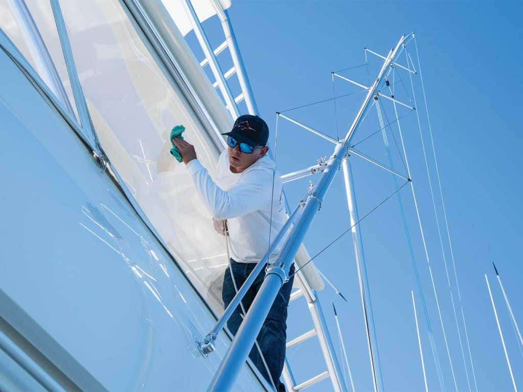 A man cleaning an enclosure on a sport-fishing boat.