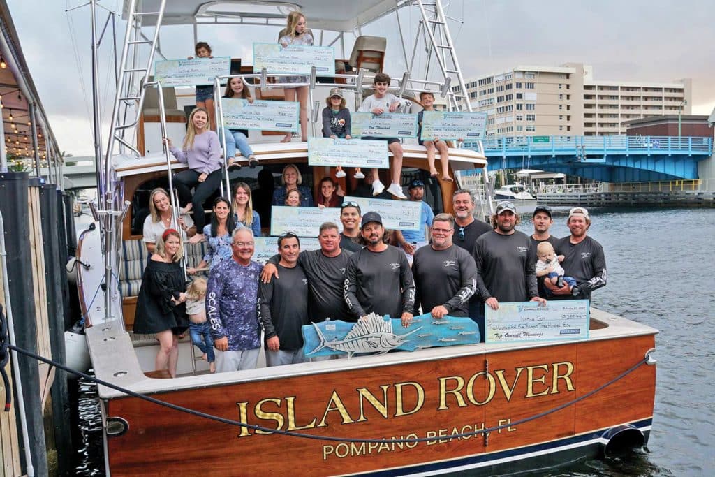 A sport-fishing team stands on a boat's cockpit and celebrates a win.