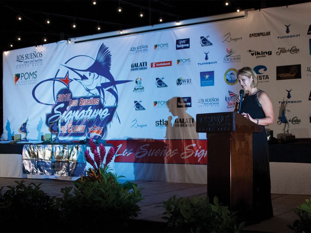A woman stands behind a podium at a sport-fishing tournament ceremony.