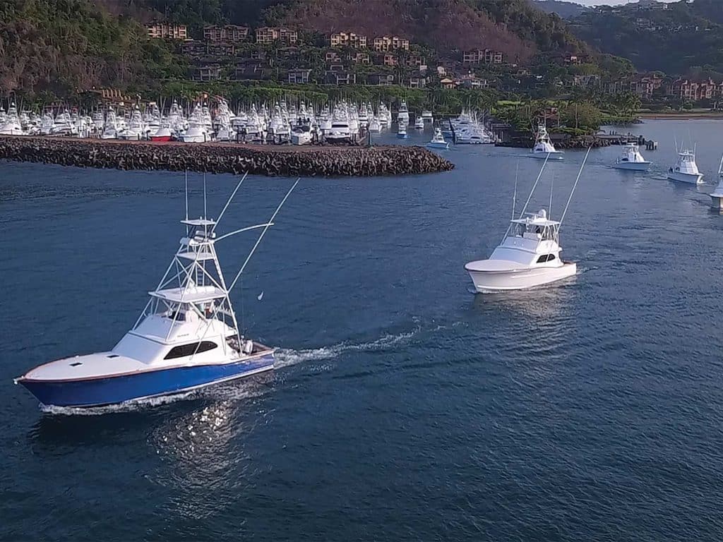 A fleet of sport fishing charter boats pull out of a harbor.