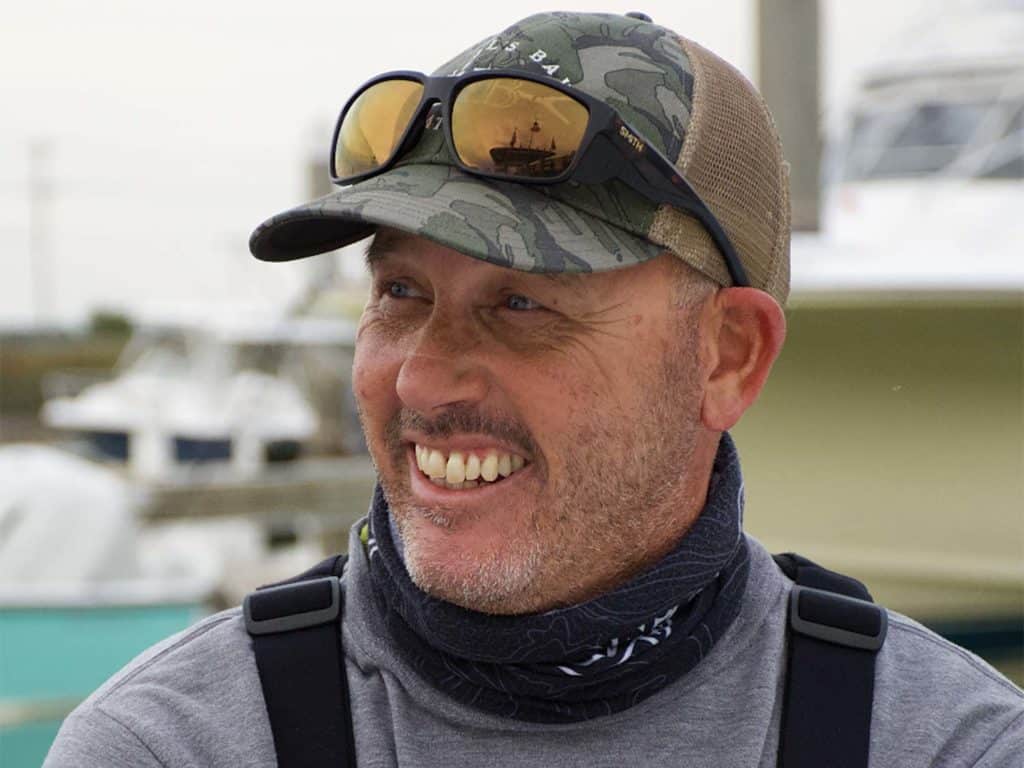 A boat captain wearing a cap and a pair of shades.