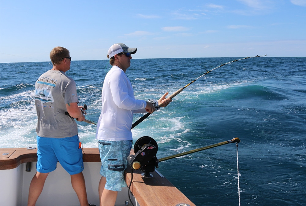 An angler in the corner of a sportfishing boat, fighting a marlin.