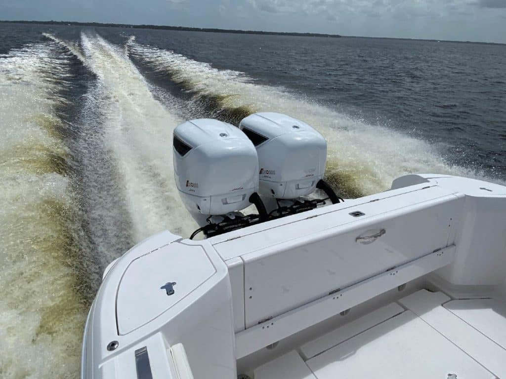 Two diesel outboard motors attached to a boat transom out on the water.