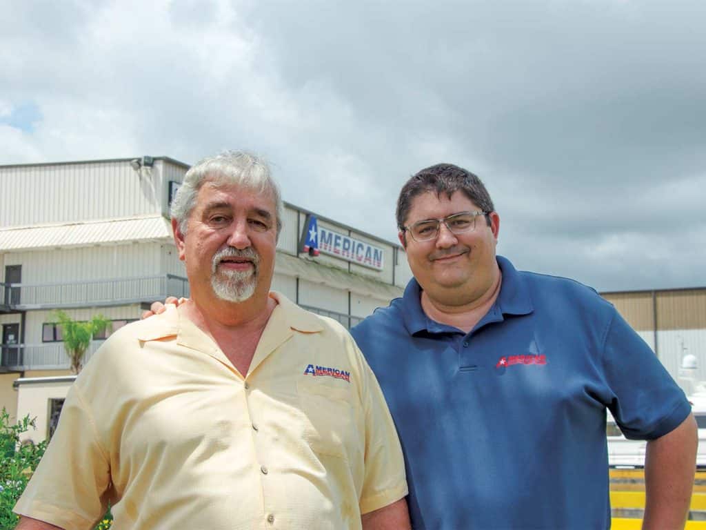 Two men posting outside of American Custom Yachts boat factory.