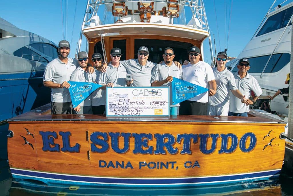 A fishing team stands on the deck of a boat with their winning showcases.