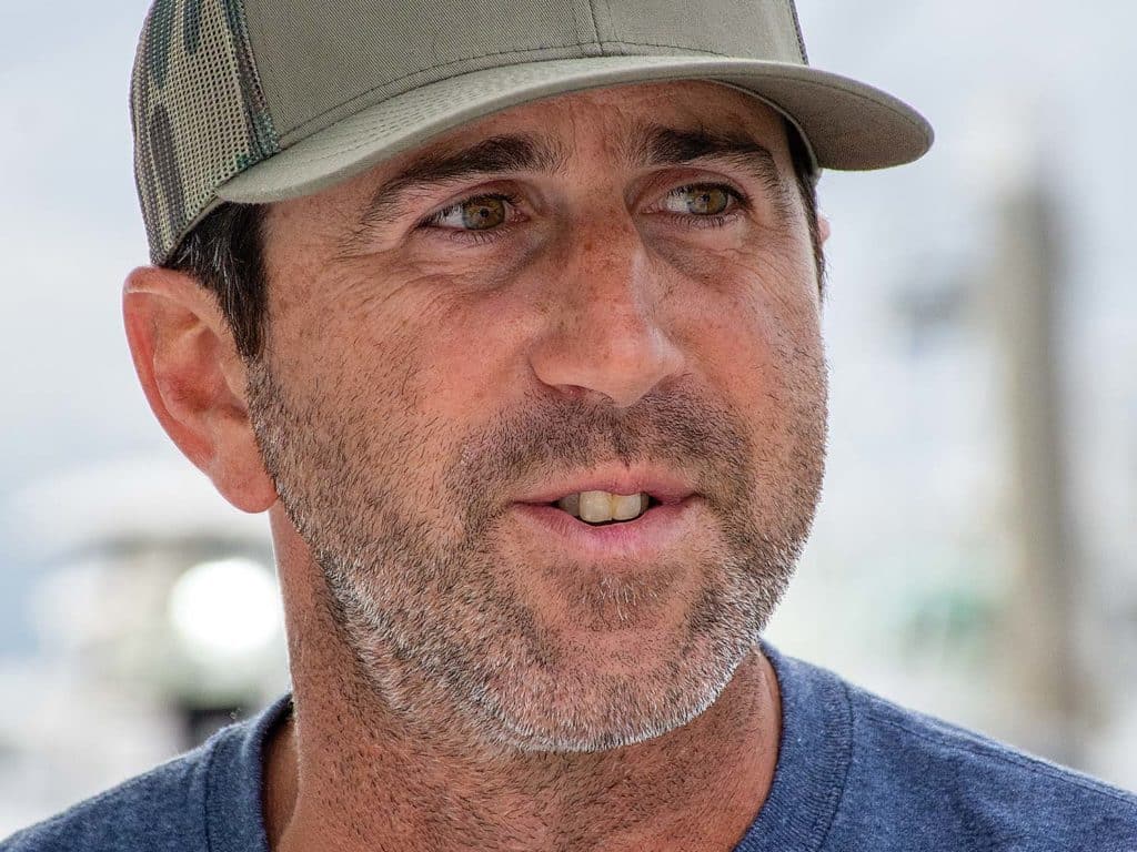 A boat captain wearing a cap and a pair of shades.