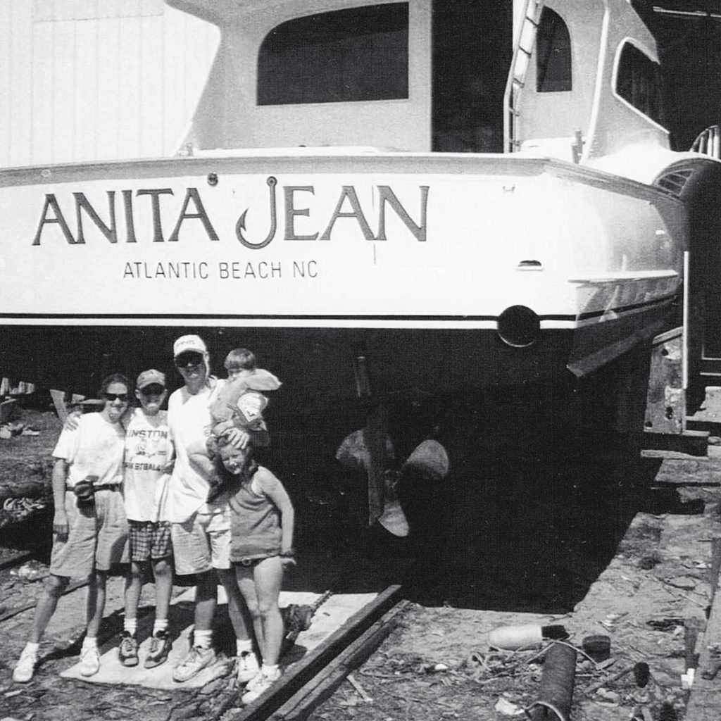 A family of five stand beside their new sport-fishing boat that's held in dry dock.