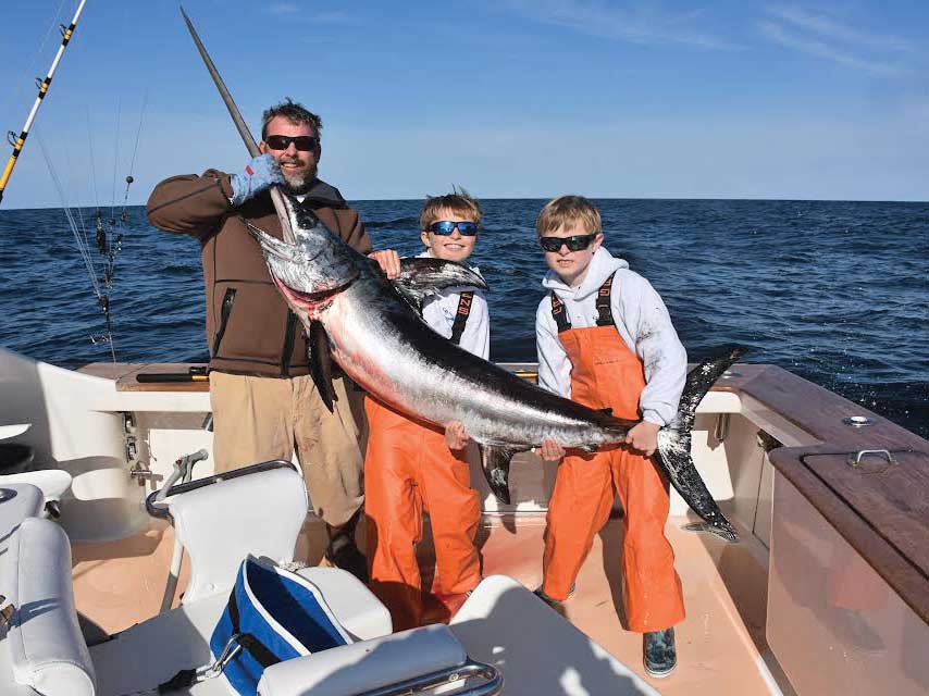 A man and two sons holding up a swordfish.