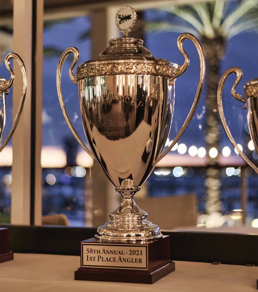 A gleaming trophy on a table with the plaque "1st Place Angler"