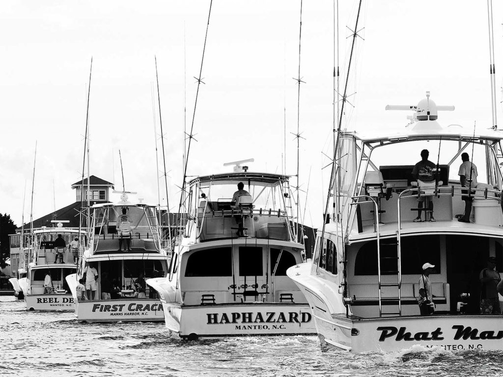 A fleet of sport fishing boats leaving a marina.