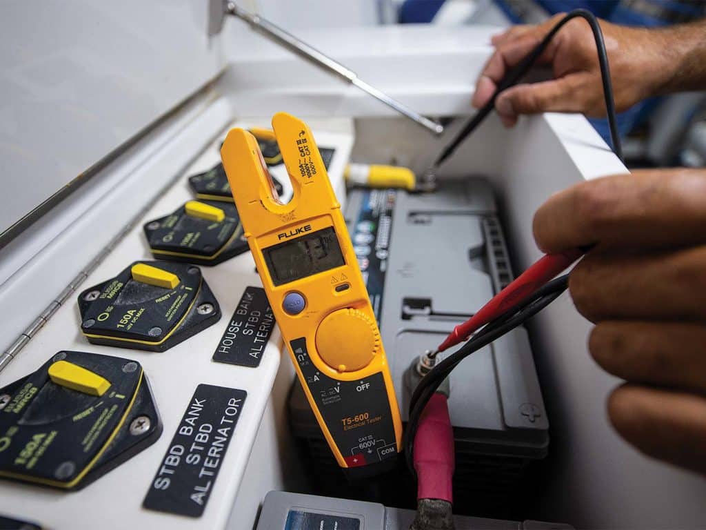 A person tests a boat engines electrical issues using a Fluke Multimeter at various circuit connections.