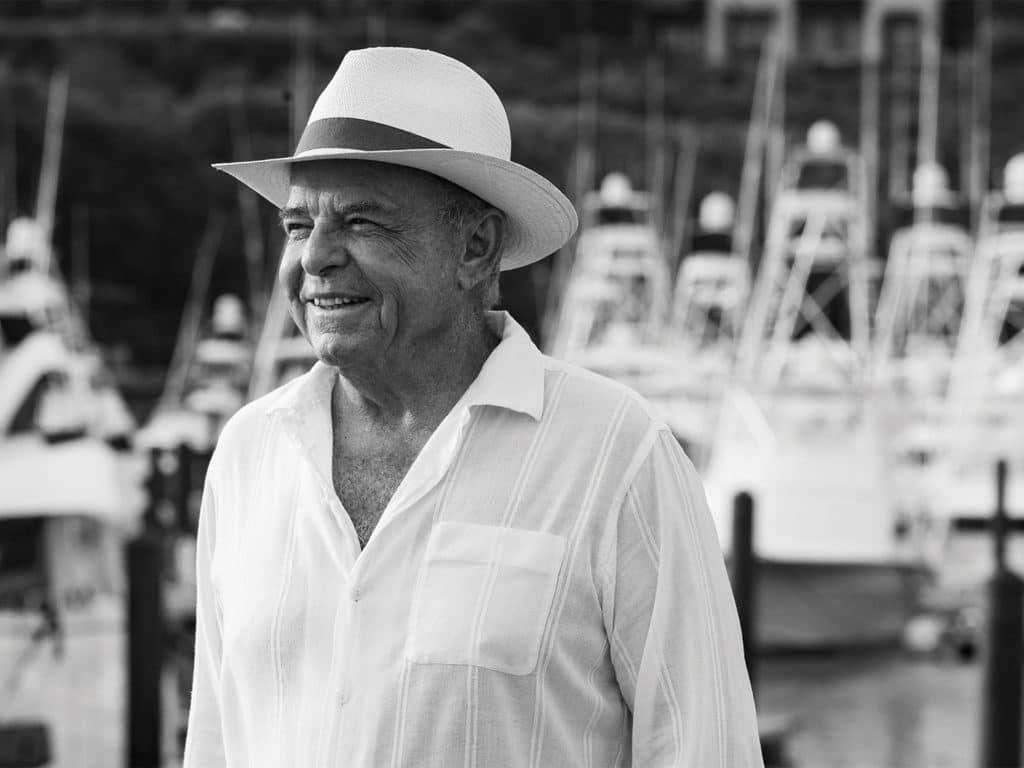 A black and white image of a man standing on a boat dock.