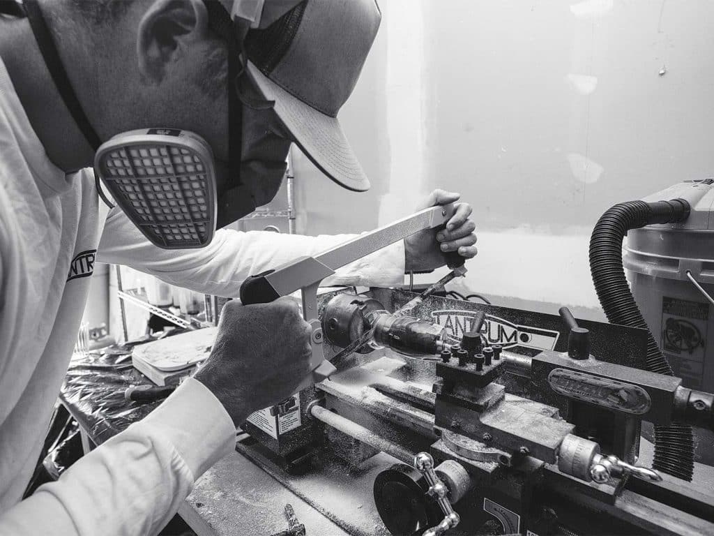 A man works at a craft station making and adjusting custom lures.