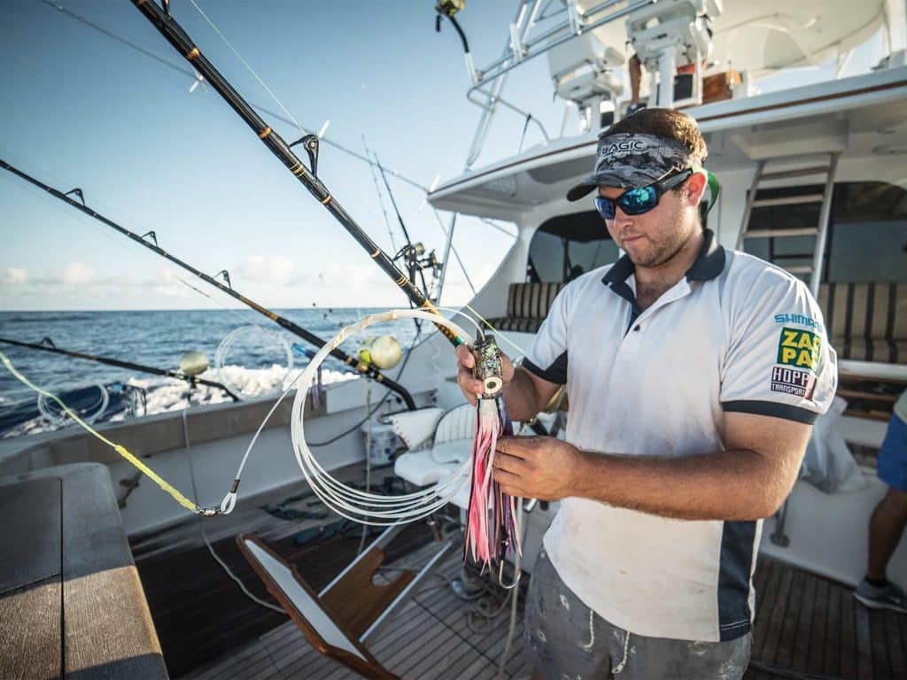 An angler rigs a lure onto a fishing leed and reel.