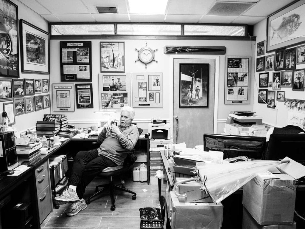 A black and white photo of a man behind a desk.