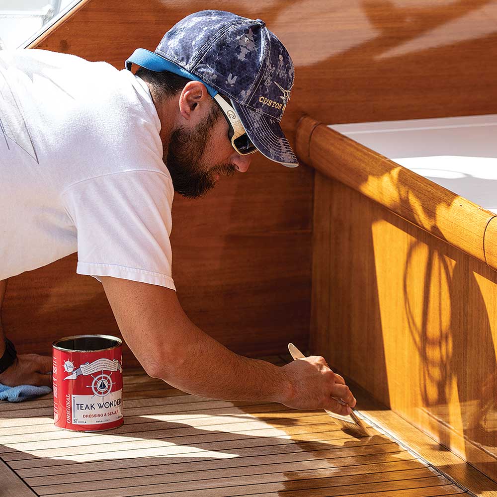 man staining teakwood deck