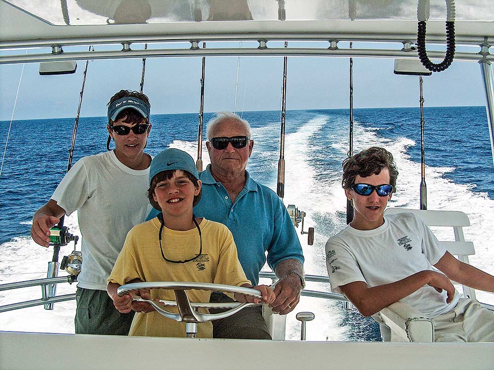 older man and three younger kids at the helm of a fishing boat