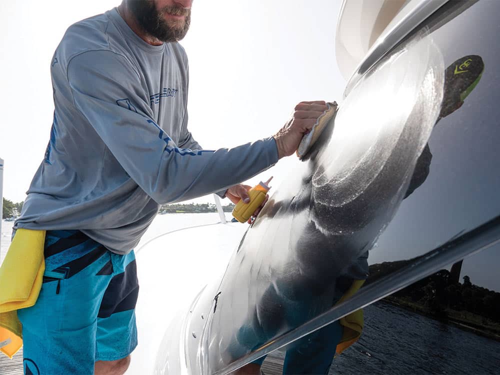 man waxing the hull of a boat