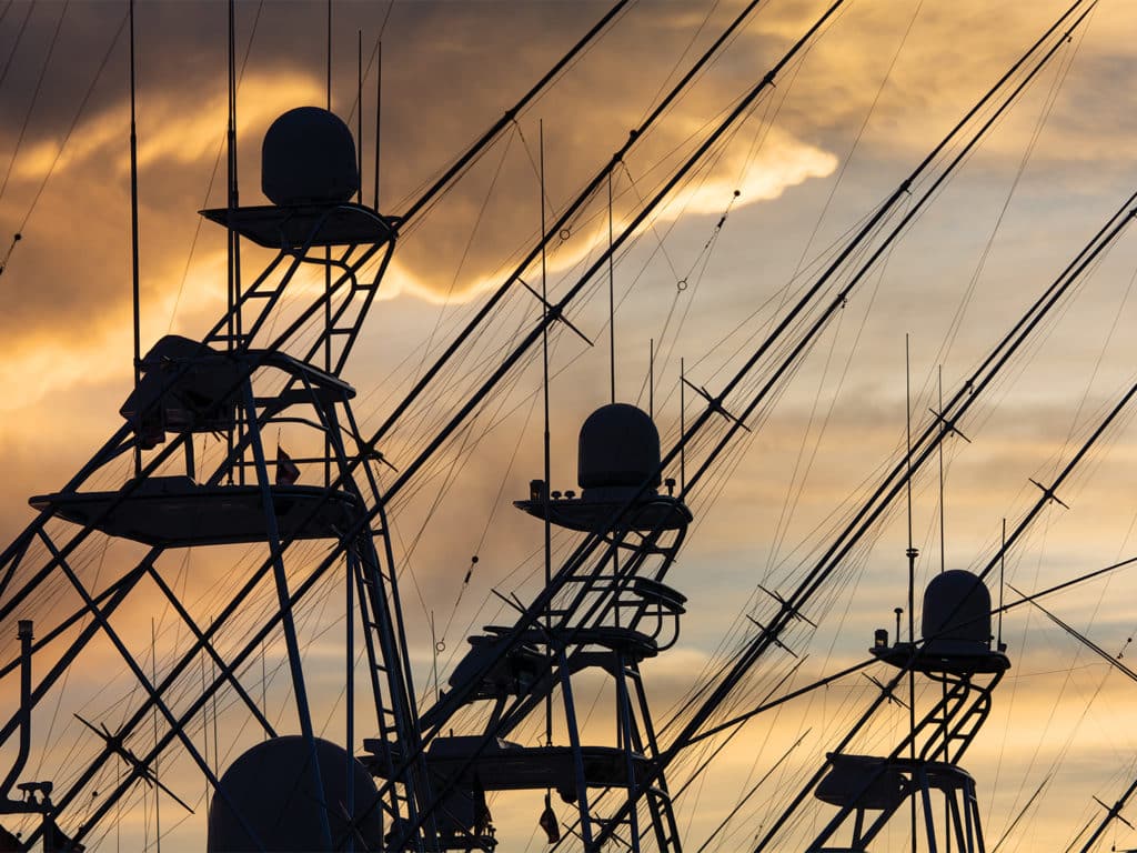 Silhouettes of sport fishing boat towers against a sunset sky.