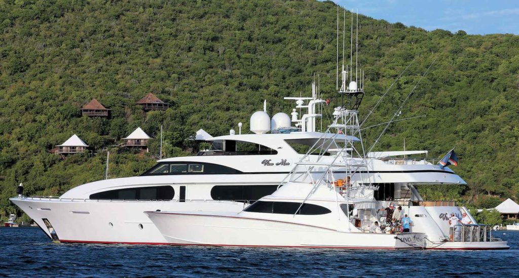 A sport fishing yacht next to a large yacht mothership.