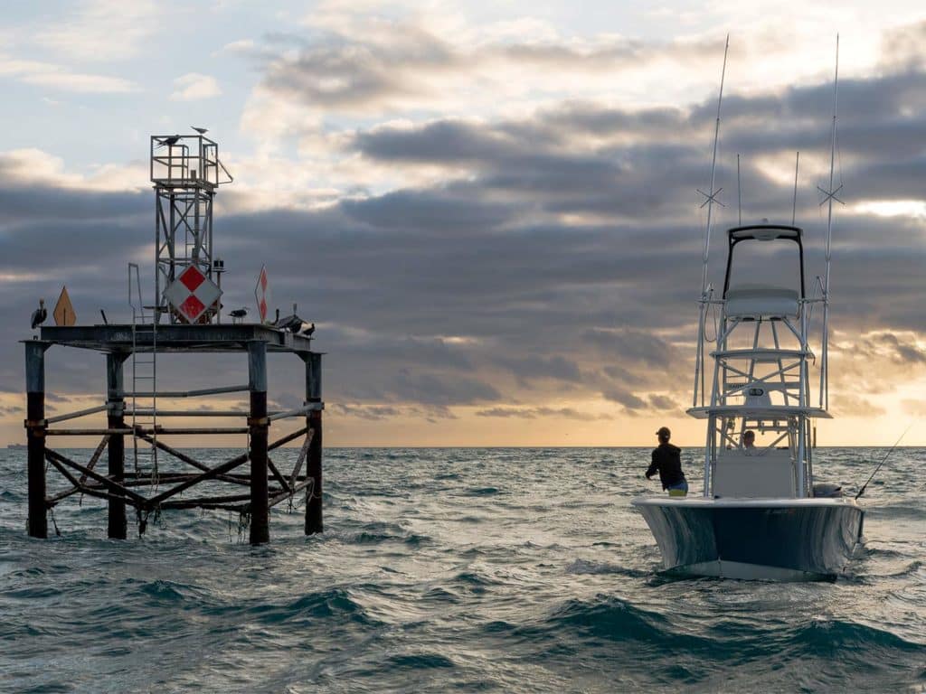 A small sport fishing boat pulls up next to a range marker in the ocean off the coast of Miami.