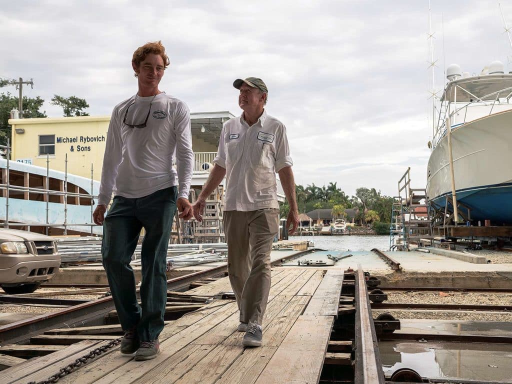 Two men walk down a boat dock.