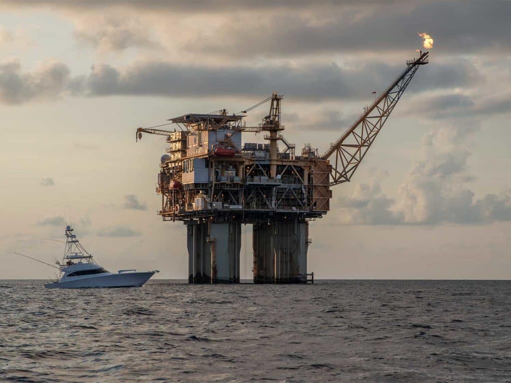 oil rig at night with a sport fishing yacht