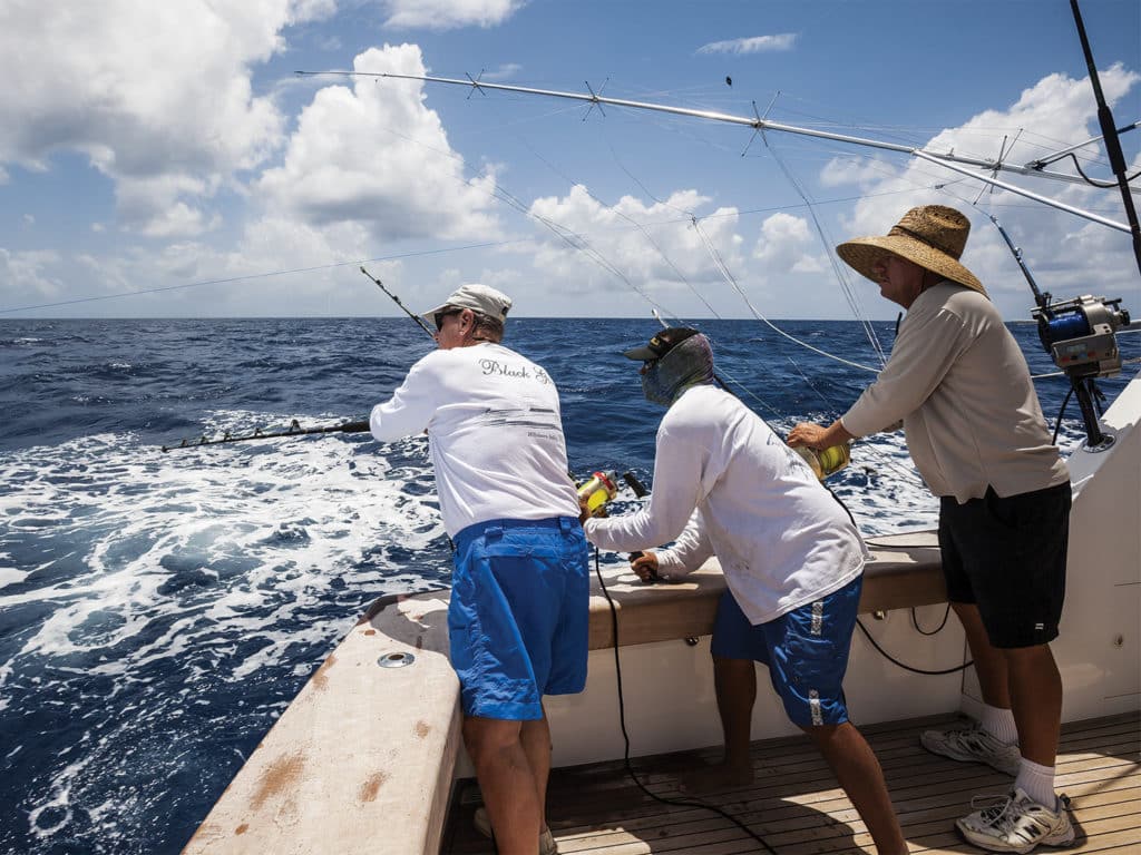 three fishermen pitch-baiting for blue marlin