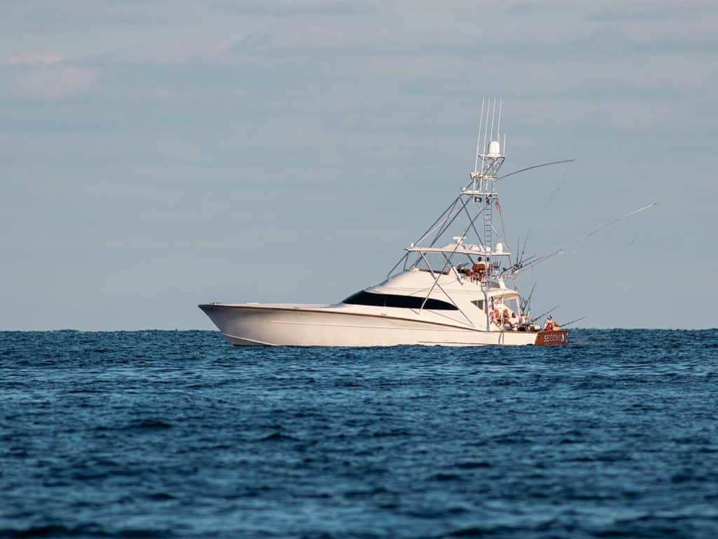 A single sport-fishing boat sailing across the horizion.