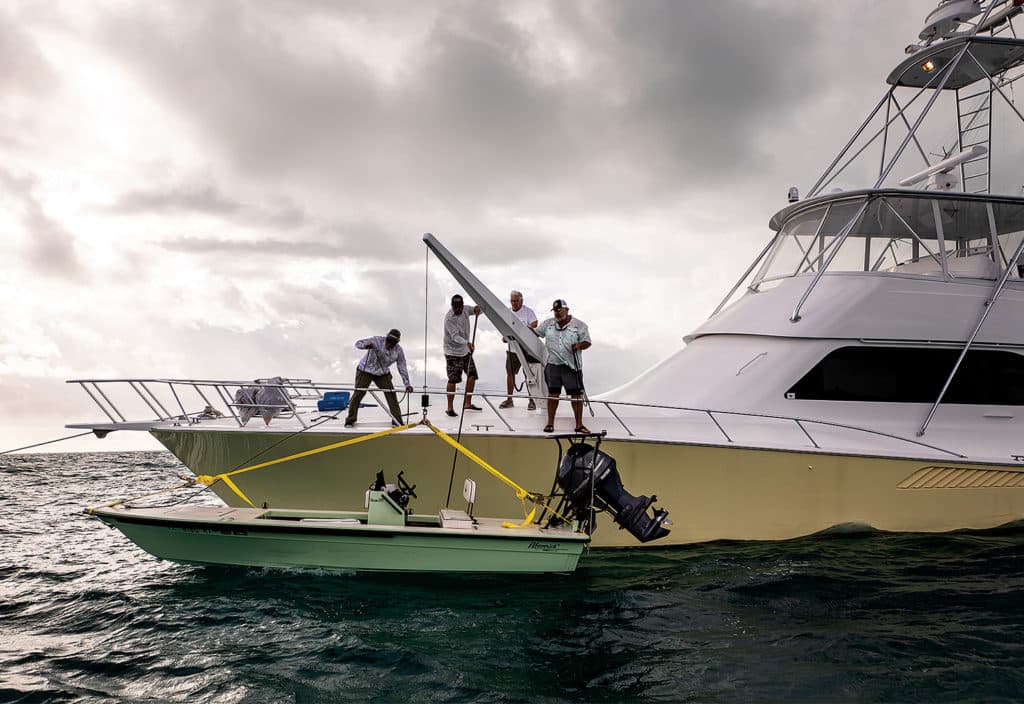 A crew lowering a skiff into the water.