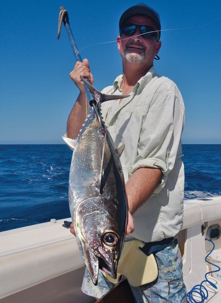 A sport-fishing angler holds up a large albacore tuna.